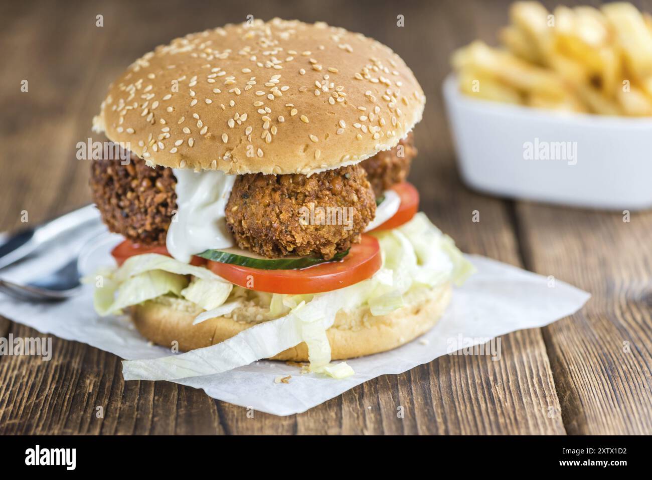 Holztisch mit einem hausgemachten Falafel-Burger (Tiefenschärfe) Stockfoto