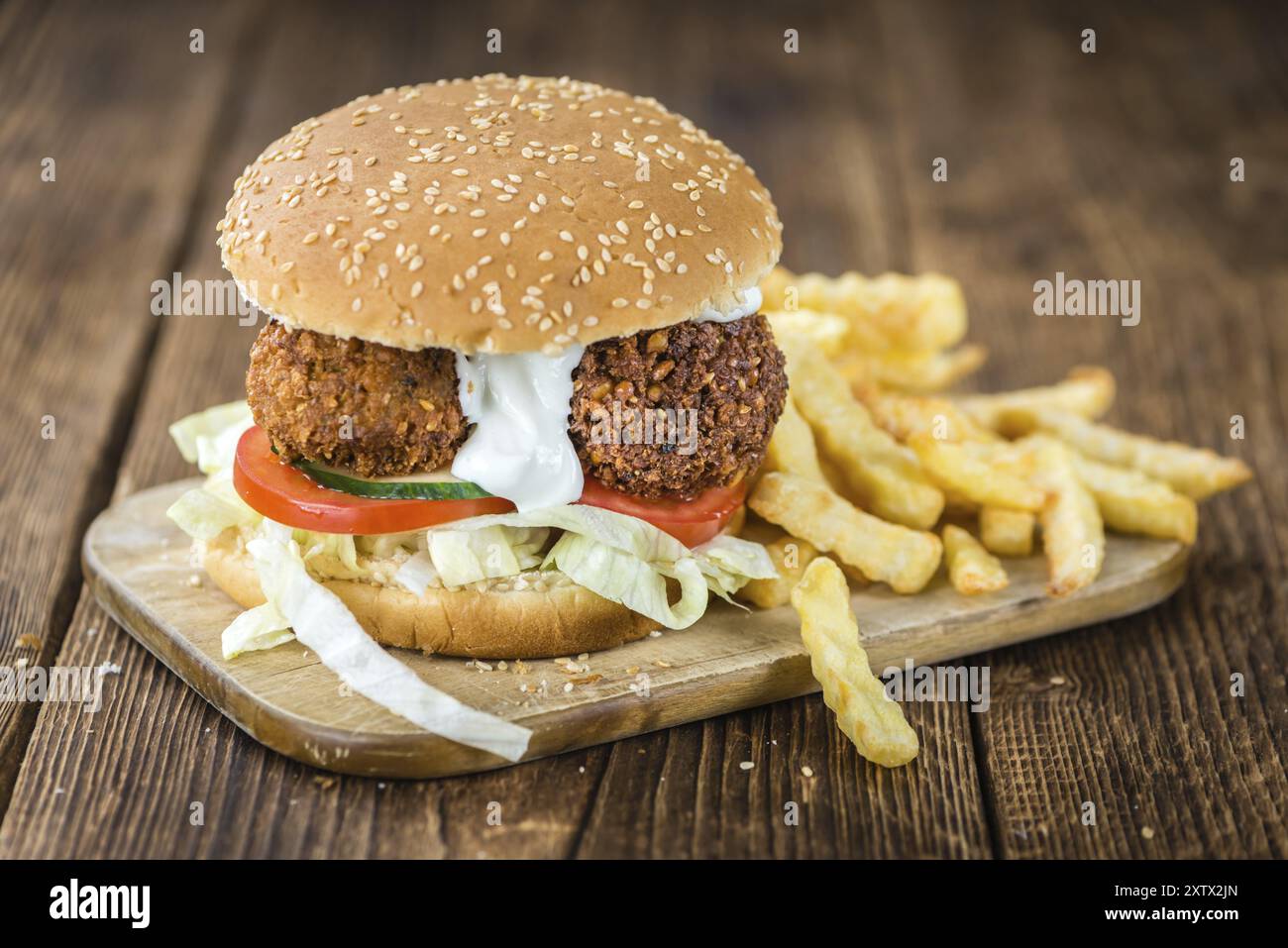 Hausgemachter Falafel Burger (detaillierte Nahaufnahme, selektiver Fokus) auf einem Holztisch Stockfoto