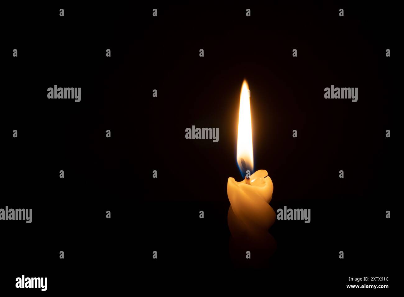 Eine einzelne brennende Kerzenflamme oder Licht leuchtet auf einer spiralförmigen weißen Kerze auf schwarzem oder dunklem Hintergrund auf dem Tisch in der Kirche zu Weihnachten, Beerdigung oder mir Stockfoto