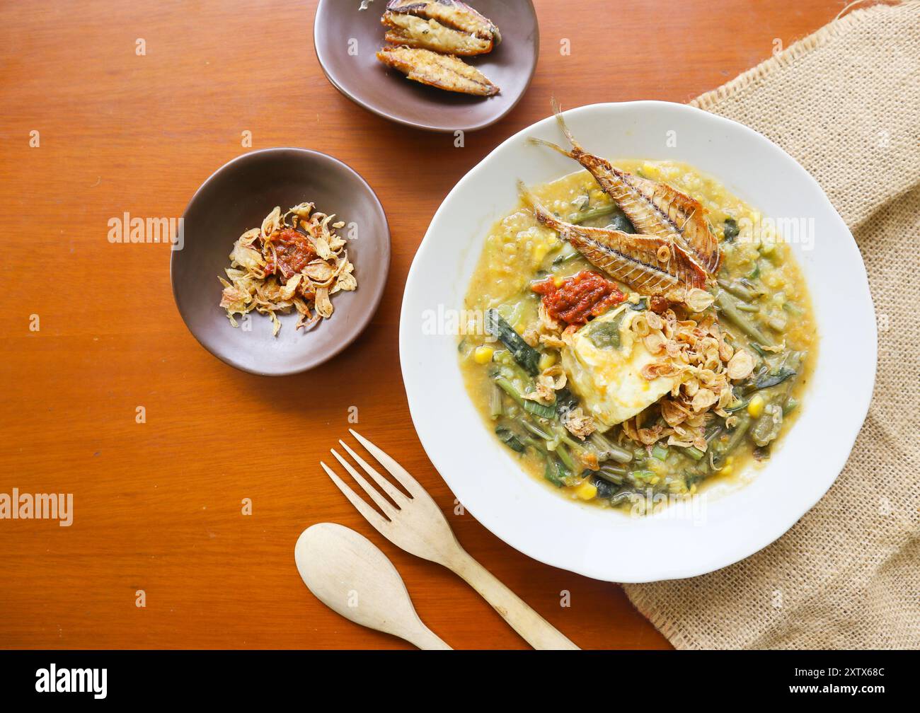 Manado Brei oder Tinutuan Brei ist traditioneller Brei. Manadonesischer Reisbrei, gemischt mit Kürbis, Mais, Gemüse. Serviert mit gesalzenem Tofu Stockfoto