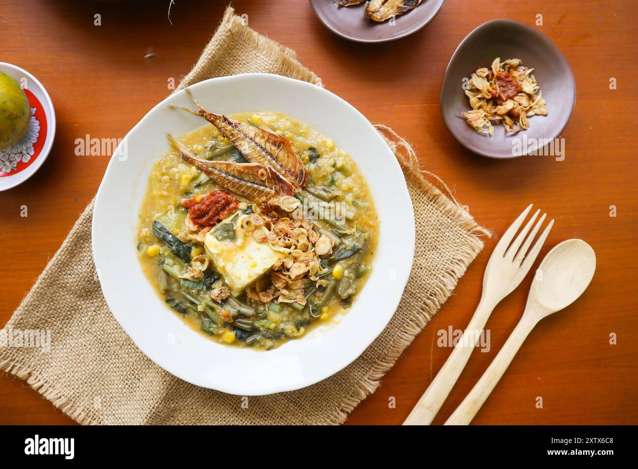 Manado Brei oder Tinutuan Brei ist traditioneller Brei. Manadonesischer Reisbrei, gemischt mit Kürbis, Mais, Gemüse. Serviert mit gesalzenem Tofu Stockfoto