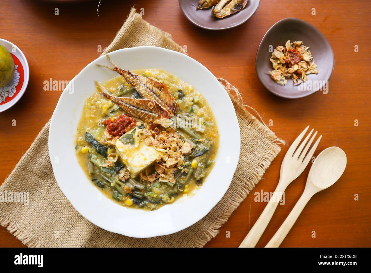 Manado Brei oder Tinutuan Brei ist traditioneller Brei. Manadonesischer Reisbrei, gemischt mit Kürbis, Mais, Gemüse. Serviert mit gesalzenem Tofu Stockfoto