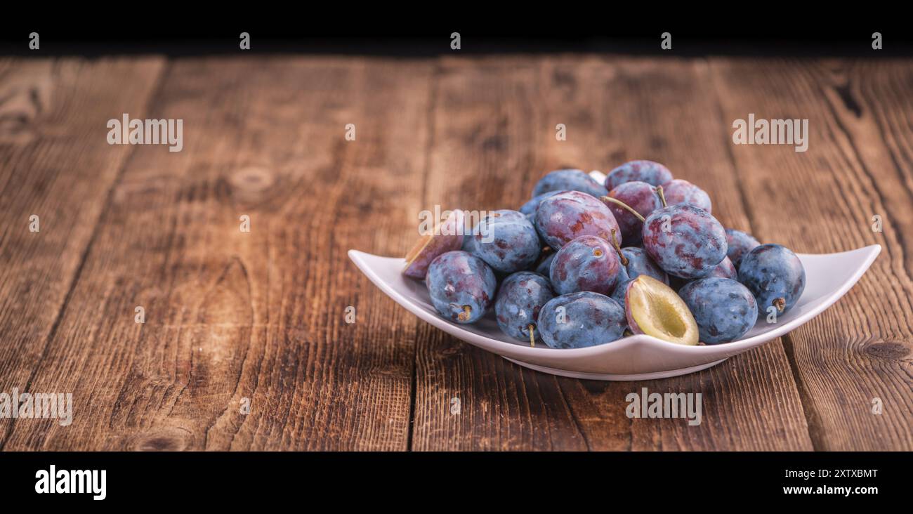 Pflaumen auf einem alten Holztisch als detaillierte Nahaufnahme, selektiver Fokus Stockfoto