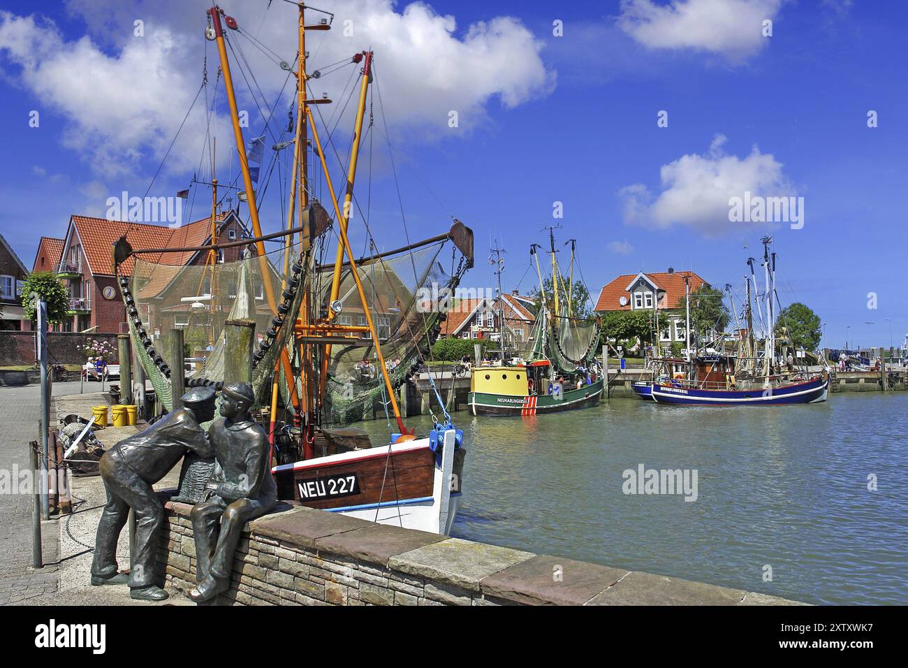 Der Hafen von Neuharlingersiel, Norddeutschland, Ostfriesland, Fischerdenkmal vor Fischerbooten, Neuharlingersiel, Niedersachsen, Bundesrepublik Deutschland Stockfoto