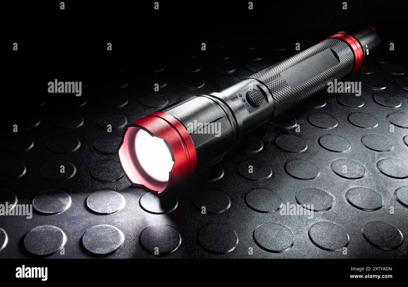 Aufladbare schwarze und rote Metalltaschenlampe mit aktivierter LED, ideal für Stromausfälle und Hurrikane anderer Naturkatastrophen. Stockfoto