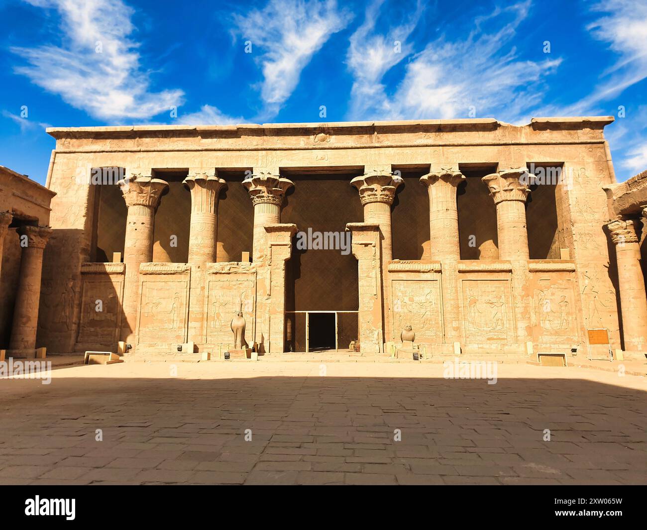 Innenhof mit zwei Granitstatuen von Horus, die den Eingang in den Tempel des Horus in Edfu bewachen, der während der ptolemäischen Ära zwischen 237 und 57 v. Chr. in der Nähe von Assuan, Ägypten erbaut wurde Stockfoto