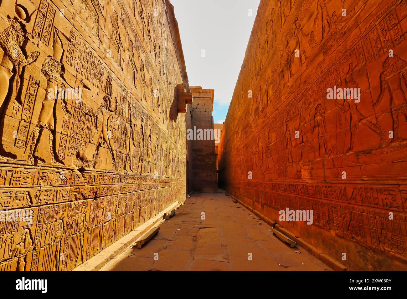 Üppige gelbe Sandsteinmauern, die mit der Geschichte von Horus und ptolemäischen Königen im Tempel des Horus in Edfu verziert sind, der während der ptolemäischen Ära zwischen 237 und 57 v. Chr. in der Nähe von Assuan, Ägypten, erbaut wurde Stockfoto