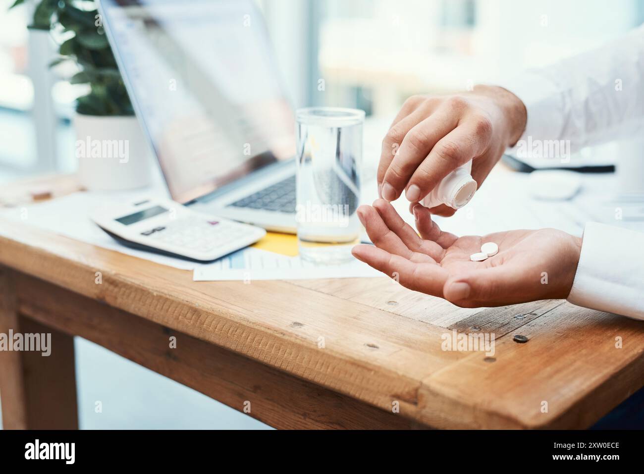 Geschäftsmann, Laptop und Pillen mit Wasser für ärztliche Verschreibung oder tägliche Dosierung im Büro. Nahaufnahme von Mitarbeiterhänden mit Mineralflüssigkeit für Stockfoto