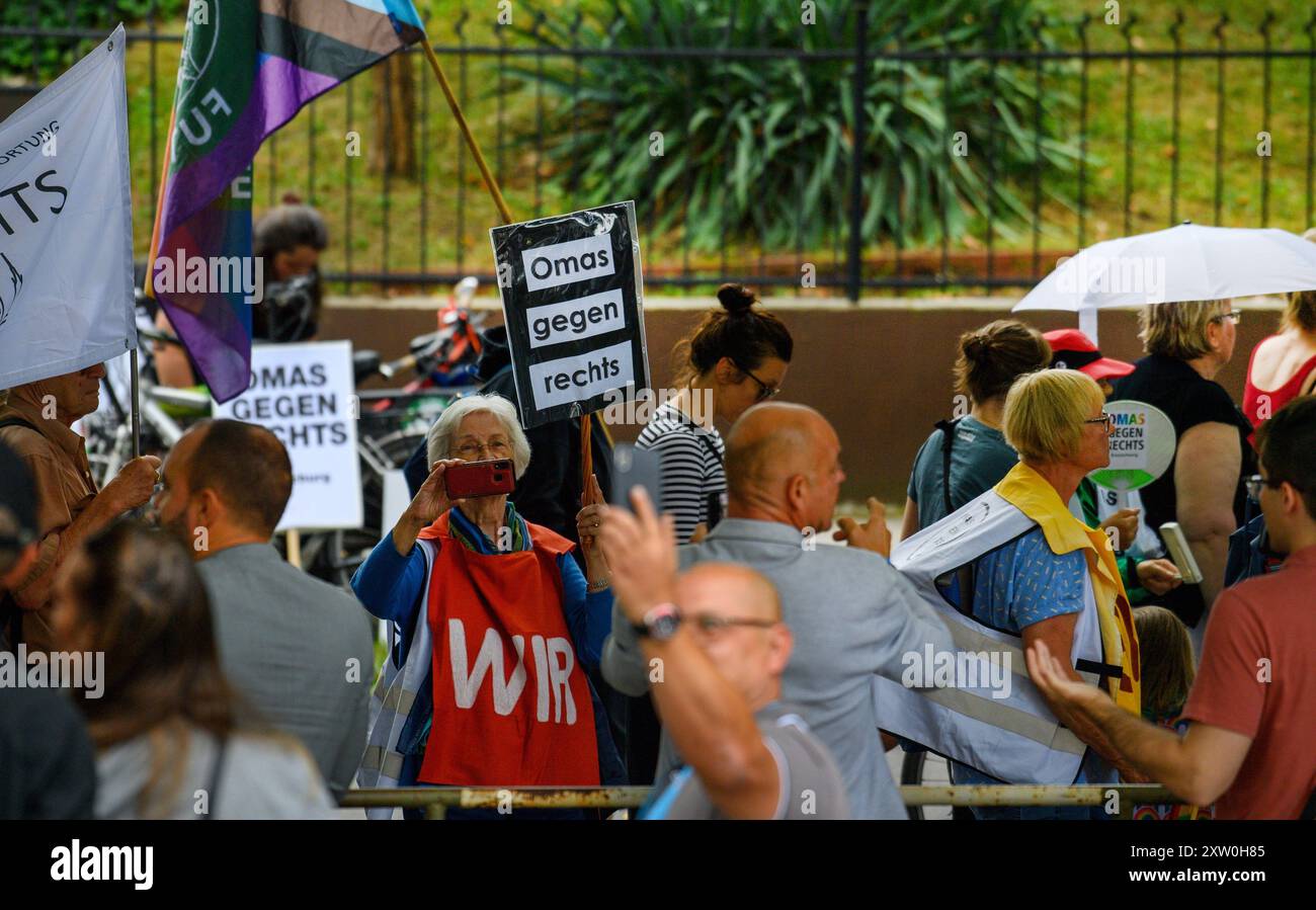 Magdeburg, Deutschland. August 2024. Demonstranten protestieren gegen die AfD-Parteikonferenz Sachsen-Anhalt und gehen am Veranstaltungsort vorbei mit Schildern mit der Aufschrift "Oma Against the Right", während ein Delegierter fotografiert. Die AfD Sachsen-Anhalt kam in Magdeburg zusammen, um unter anderem einen neuen Landesvorstand zu wählen. Quelle: Klaus-Dietmar Gabbert/dpa/Alamy Live News Stockfoto