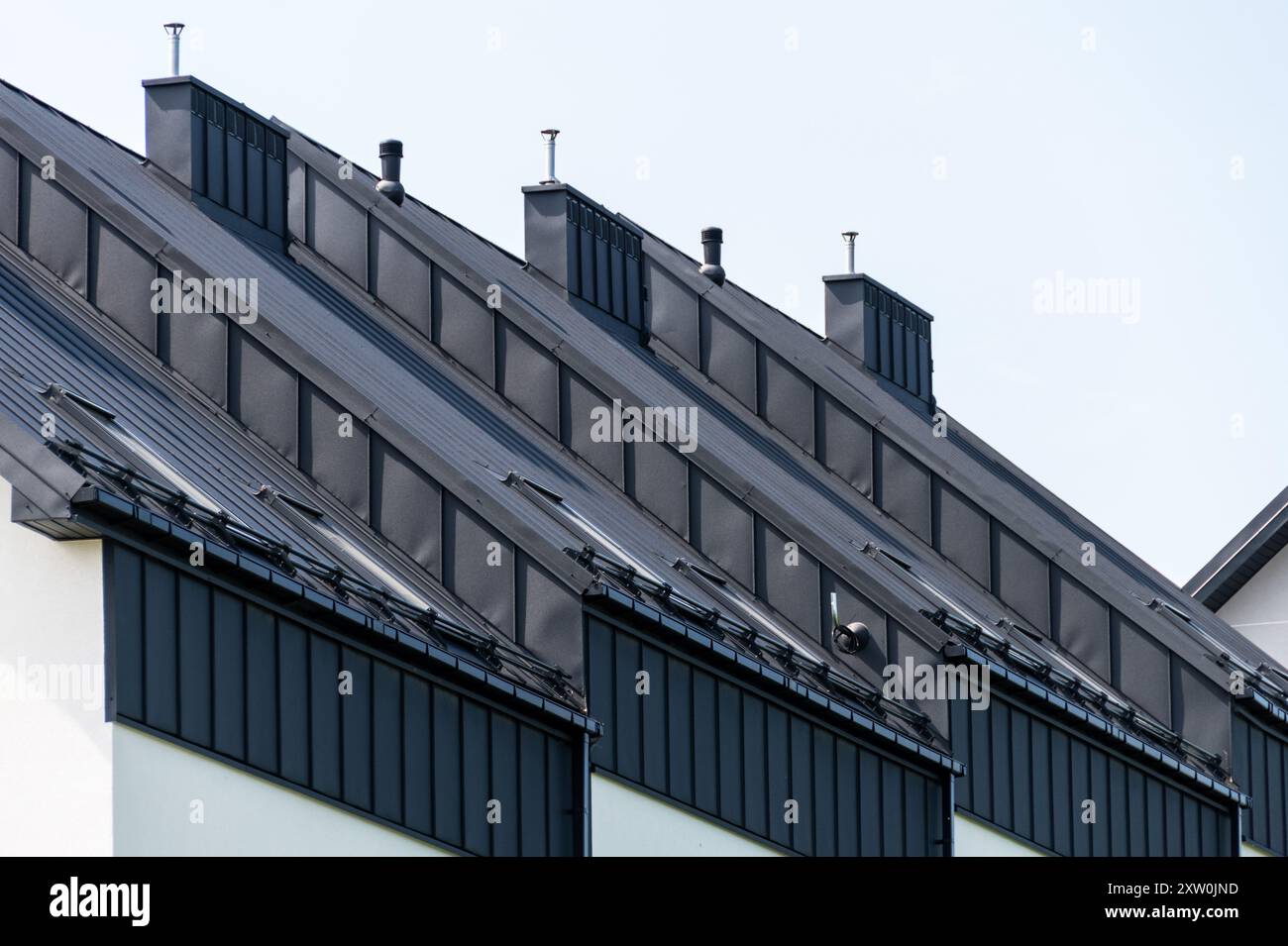 Moderne Dächer mit stilvollem schwarzem Metalldesign, ausgestattet mit Schornsteinen und geneigten Winkeln, die moderne architektonische Trends in Res demonstrieren Stockfoto
