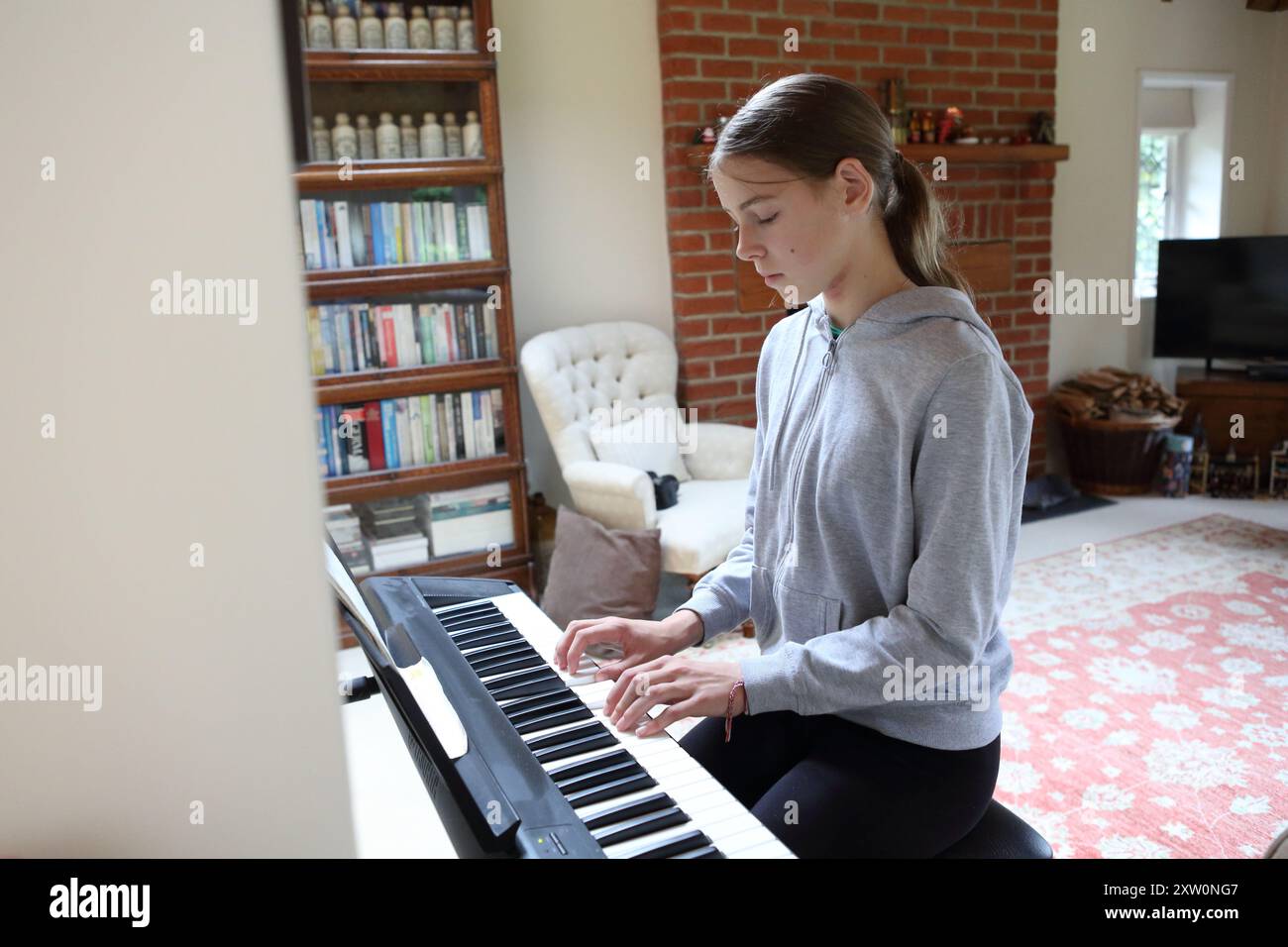 Mädchen spielt Tastatur in der Lounge zu Hause - Musik Tastatur Tasten musikalische Kreativität Melodie Üben Üben Stockfoto