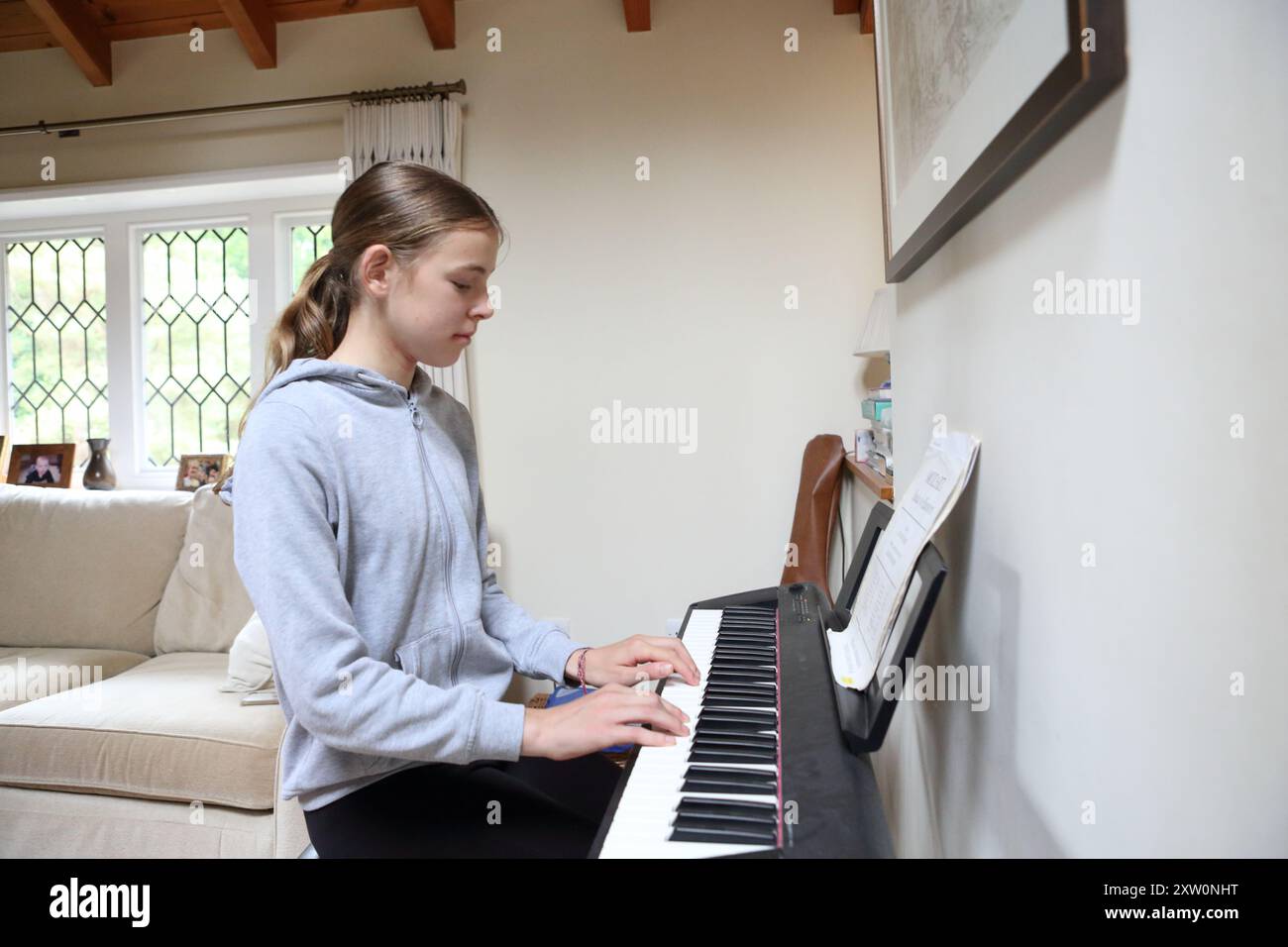 Mädchen spielt Tastatur in der Lounge zu Hause - Musik Tastatur Tasten musikalische Kreativität Melodie Üben Üben Stockfoto