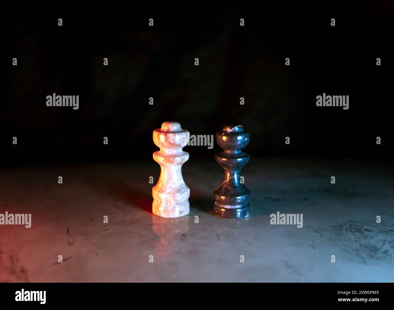 Schließen Sie zwei Schachfiguren, die auf einem Schachbrett auf dunklem Hintergrund stehen Stockfoto