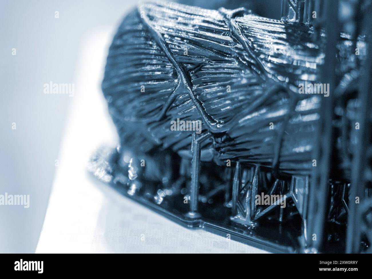 Schwarzes Modell mit Stützen, die auf 3D-Druckern in Nahaufnahme gedruckt werden. Teil des Objekts, das auf dem 3D-Drucker aus gehärtetem Gummi unter Einfluss von UV-Licht erzeugt wurde. SLA 3D-Drucktechnologie. Stereolithographie Stockfoto