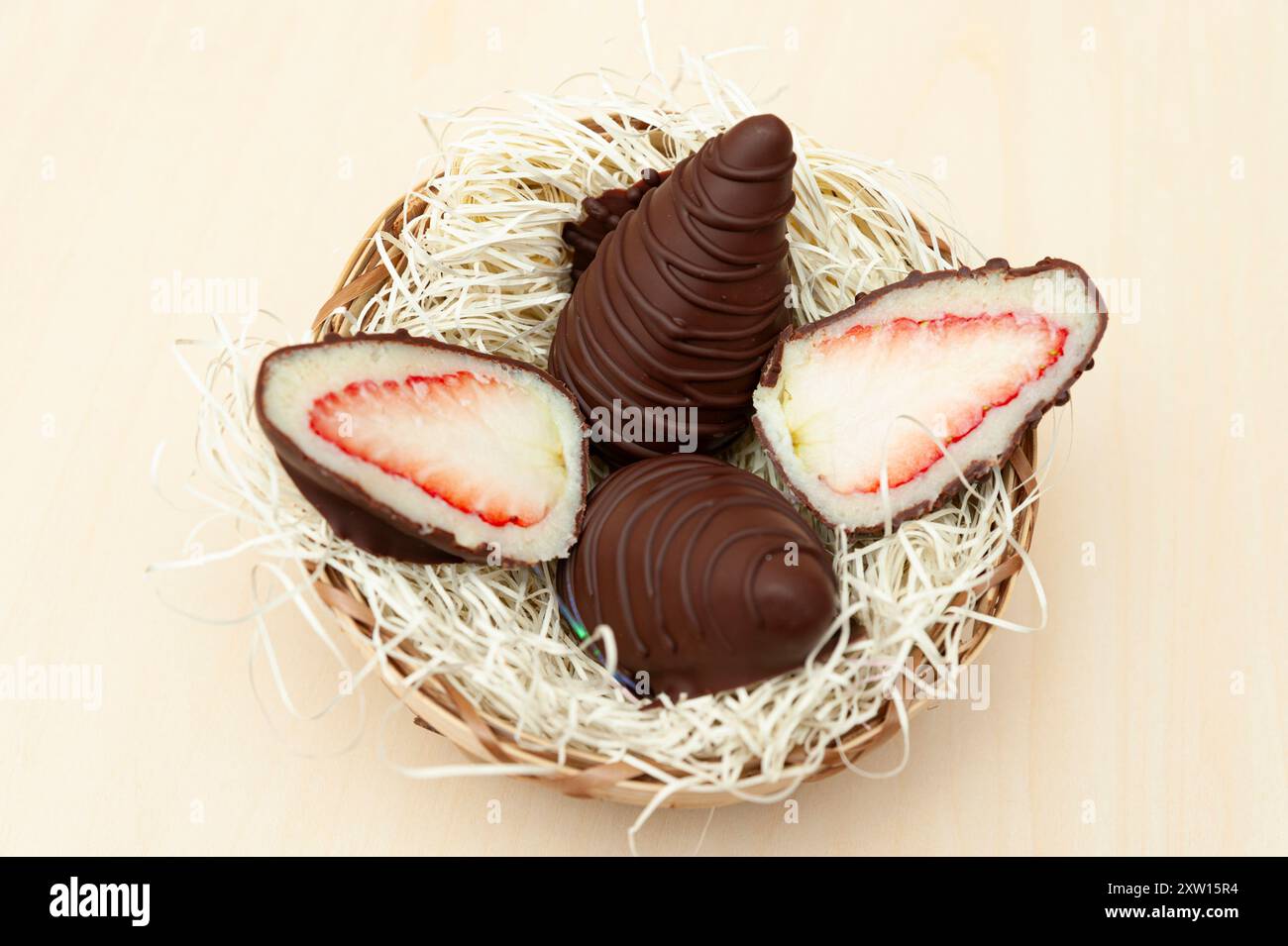 Osterei gefüllt mit Erdbeere und geriebener Kokosnuss in Aussicht von oben isoliert auf hölzernem Hintergrund. Stockfoto