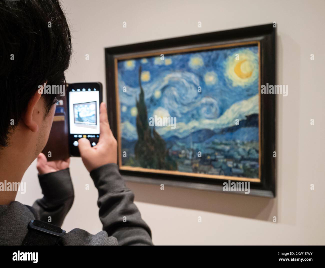 Ein Besucher des Museum of Modern Art (MoMA) in New York macht mit seinem Smartphone ein Foto von Van Goghs „The Starry Night“. Stockfoto