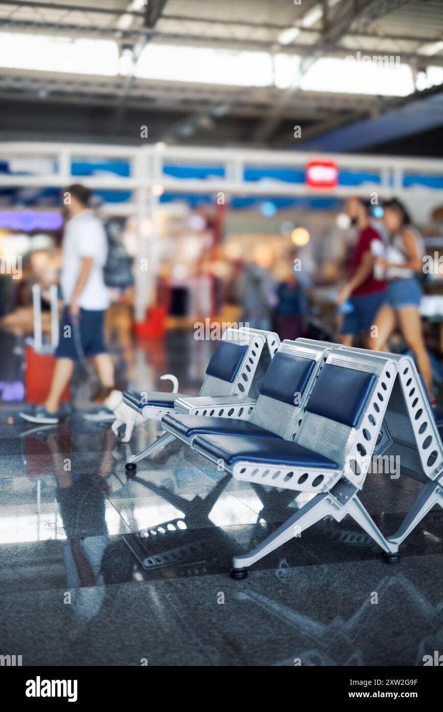 Wartebereich mit leeren Sitzplätzen im Flughafenterminal. Verschwommene Menschen auf dem Boden. Stockfoto