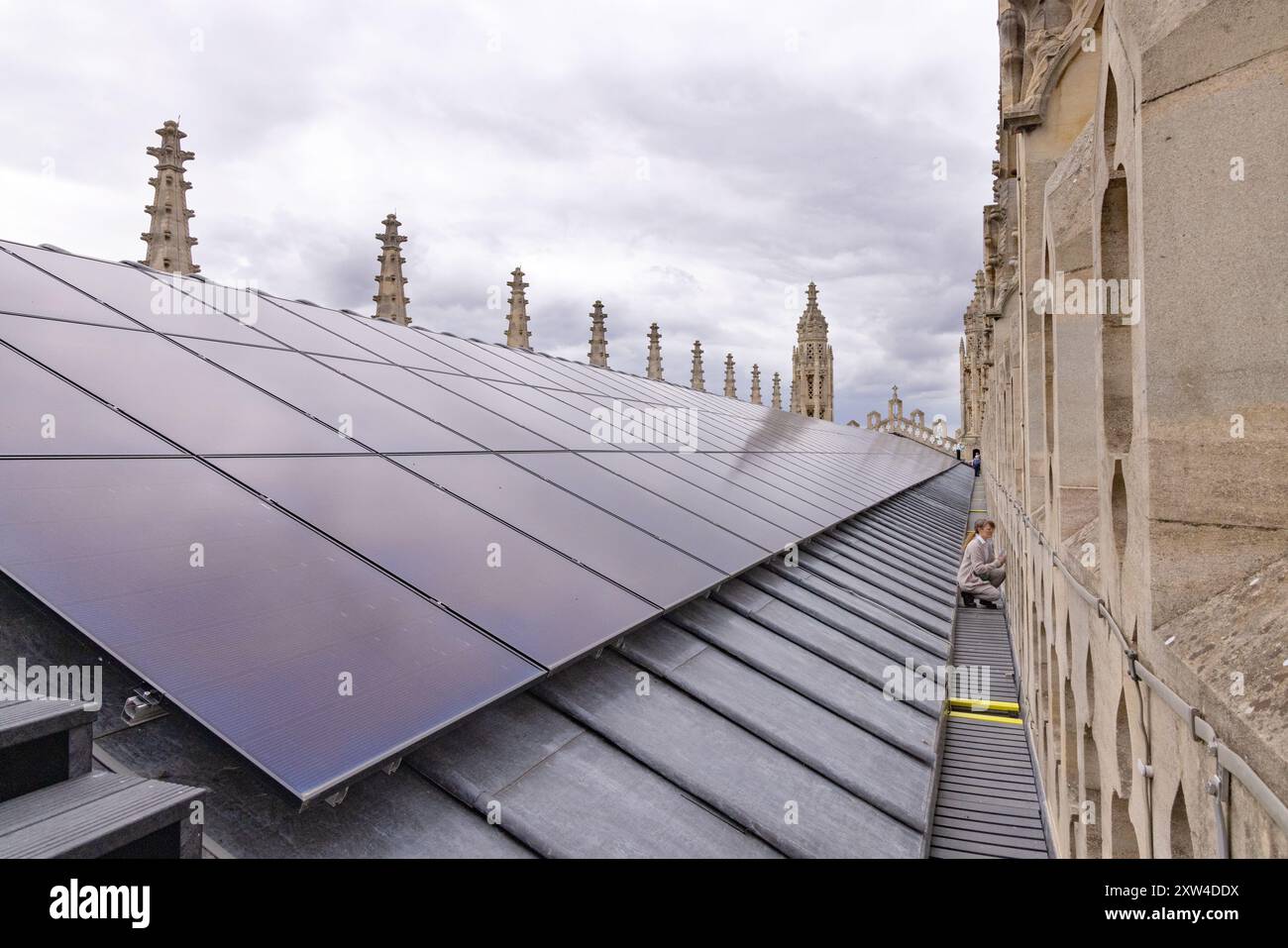 Ein Besucher auf dem Dach der Kings College Chapel als Teil einer Tour; Solarpaneele für grüne Energie oder Solarenergie installiert; Kings College Cambridge UK. Stockfoto