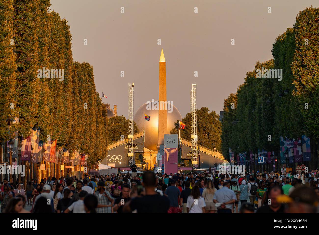 Paris, Frankreich - 10. August 2024: Menschenmassen am Place de la Concorde für den Olympischen Flammenballon im Goldenen Sonnenuntergang Stockfoto