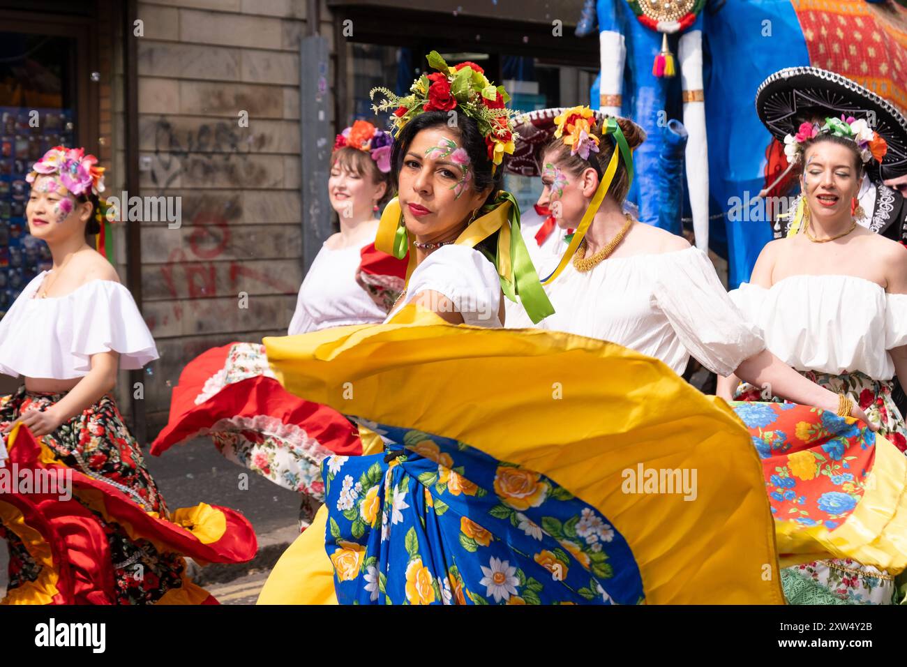 Belfast Mela Carnival Parade, eine Gruppe von Frauen in wunderschönen und raffinierten Kostümen, die im Stadtzentrum tanzen. Belfast, Großbritannien - 17. August 2024. Stockfoto