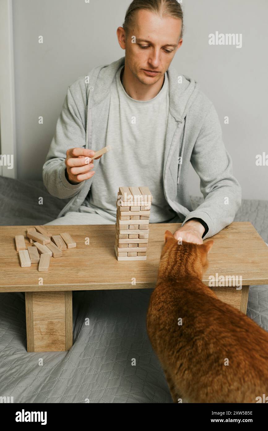 Die Person stapelt sorgfältig Blöcke in Holzturmspiel im Raum zu Hause. Digitale Detox und Konzentration. Qualitätszeit offline Stockfoto