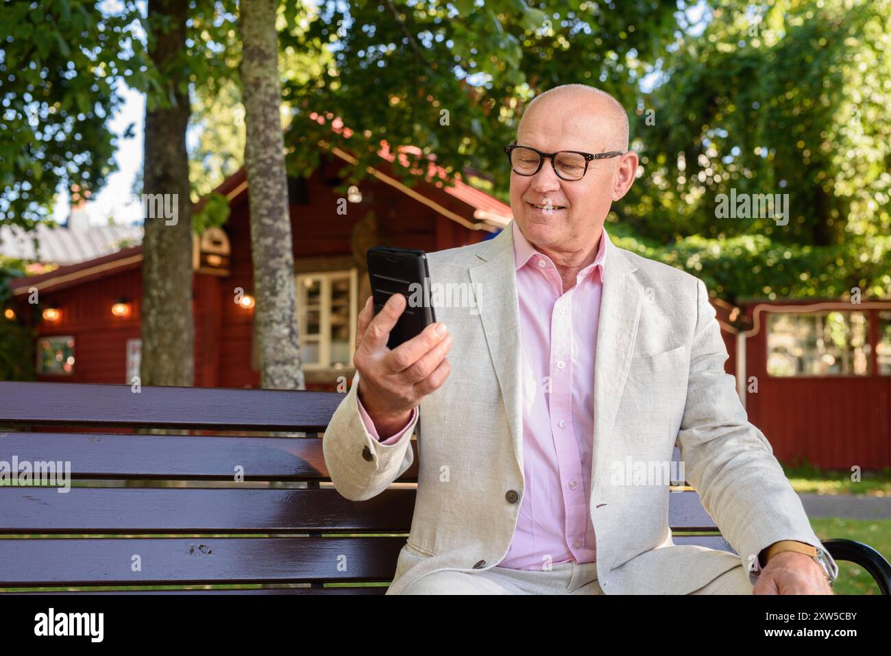 Glücklicher skandinavischer Seniorenmann, der im Sommer das Telefon im Freien nutzt Stockfoto