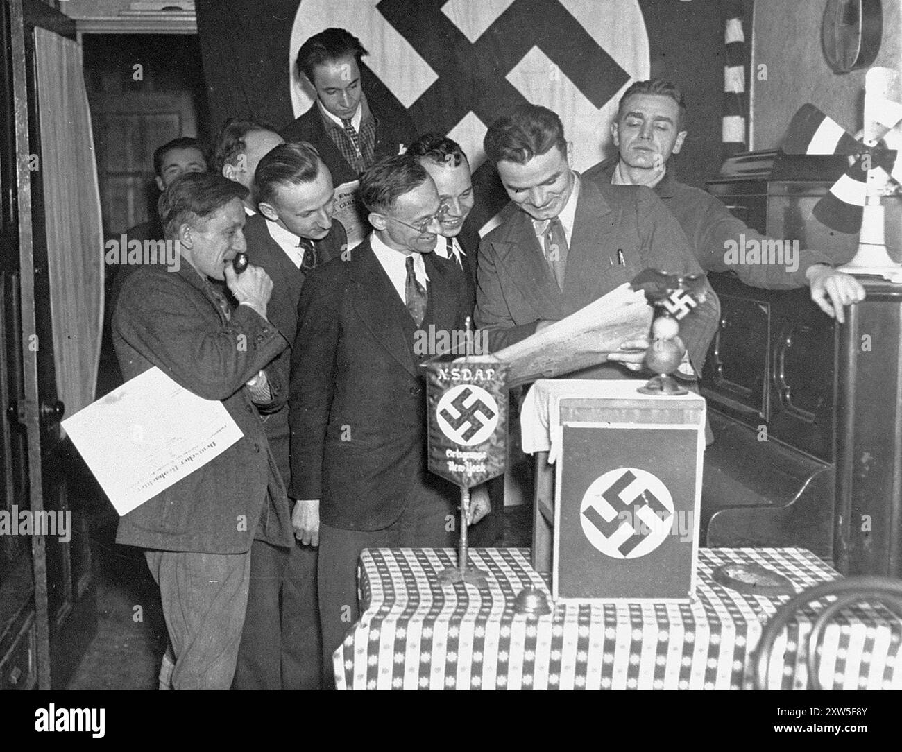 Paul Manger, wer behauptete, der Anführer einer New Yorker Nazi-Organisation zu sein, liest einen zeitungsartikel, in dem Hitlers Ernennung zum deutschen Kanzler an Mitstreitern der Nazi-Partei bei einer Feier in New York am 30 1933. Januar, dem Tag des Beitritts Hitlers zum Regierungschef, angekündigt wird. Stockfoto