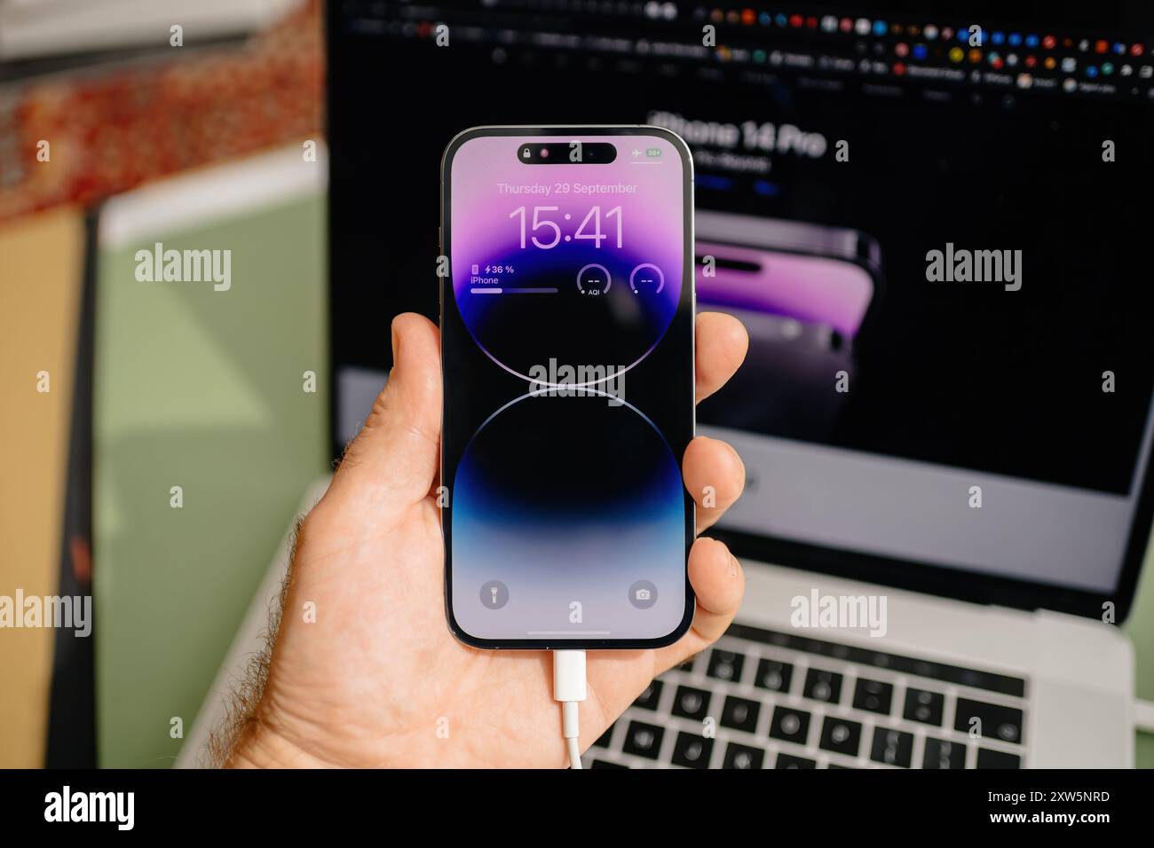 Paris, Frankreich - 29. September 2022: POV einer männlichen Hand, die das neueste iPhone 15 Pro hält, wobei die Apple Website im Hintergrund sichtbar ist und das elegante Design und die moderne Technologie des Smartphones unterstreicht Stockfoto