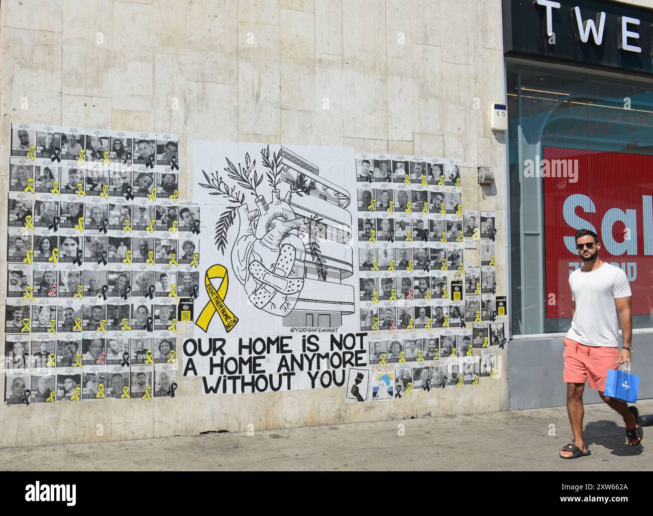 Ein Mann, der an einem Wandgemälde und Plakaten mit den Bildern der israelischen Geiseln in Gaza vorbeigeht. Dizengoff Center, Tel-Aviv, Israel. Stockfoto