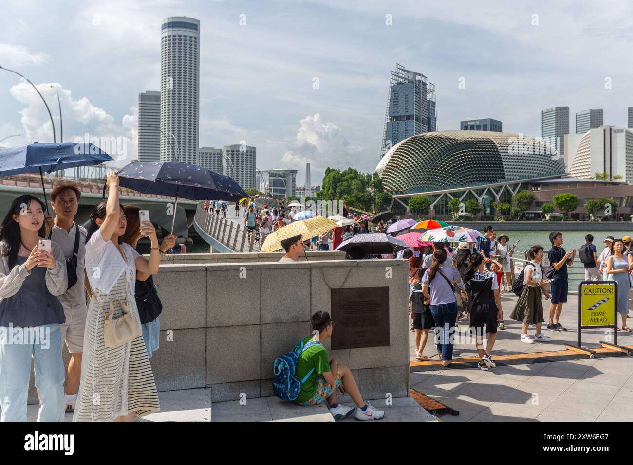 Weltweite Klimaveränderung auf höhere Temperaturen. Touristen beschatten sich mit Sonnenschirmen und ertragen die heiße Sonne, die Besichtigungstour Merlion Park. Singapur. Stockfoto