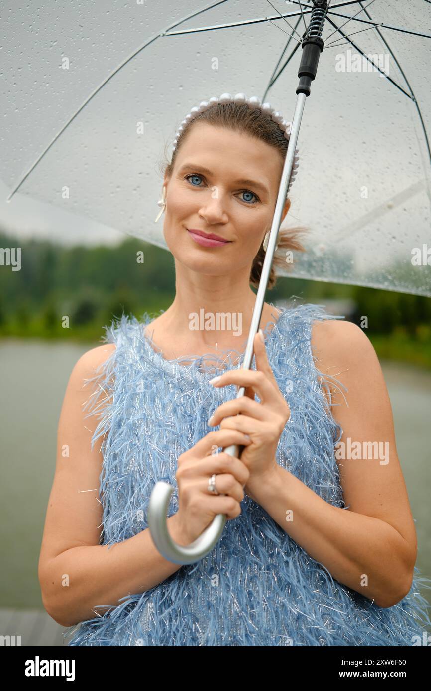 Nahporträt einer hübschen Frau mit durchsichtigem Regenschirm Stockfoto