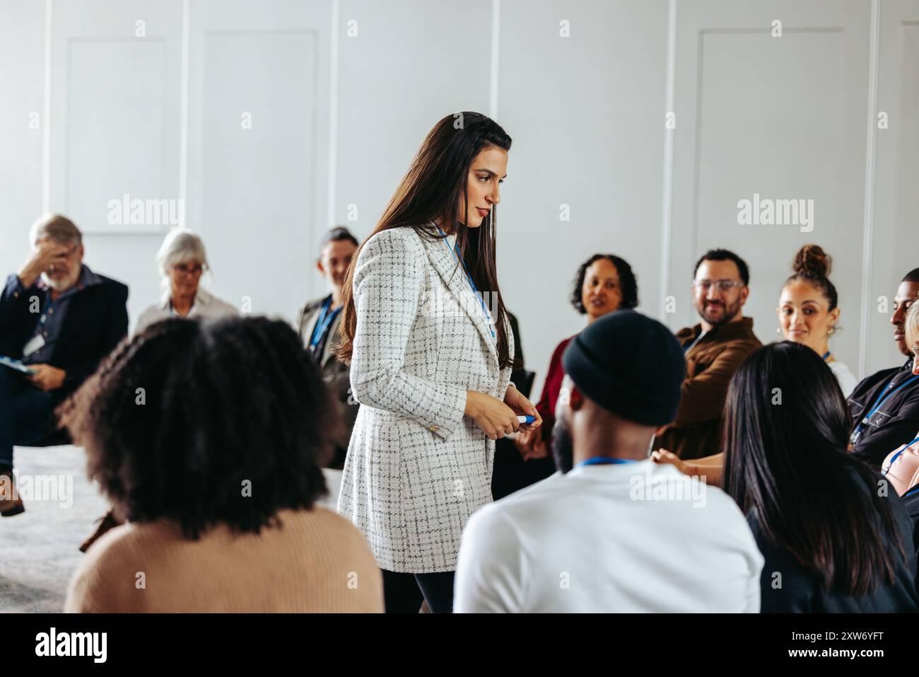 Ein Facilitator leitet eine Fragen- und Antwortsitzung mit einem vielfältigen Publikum, um die emotionale Bindung und Diskussion in einem hellen Raum zu fördern. Stockfoto