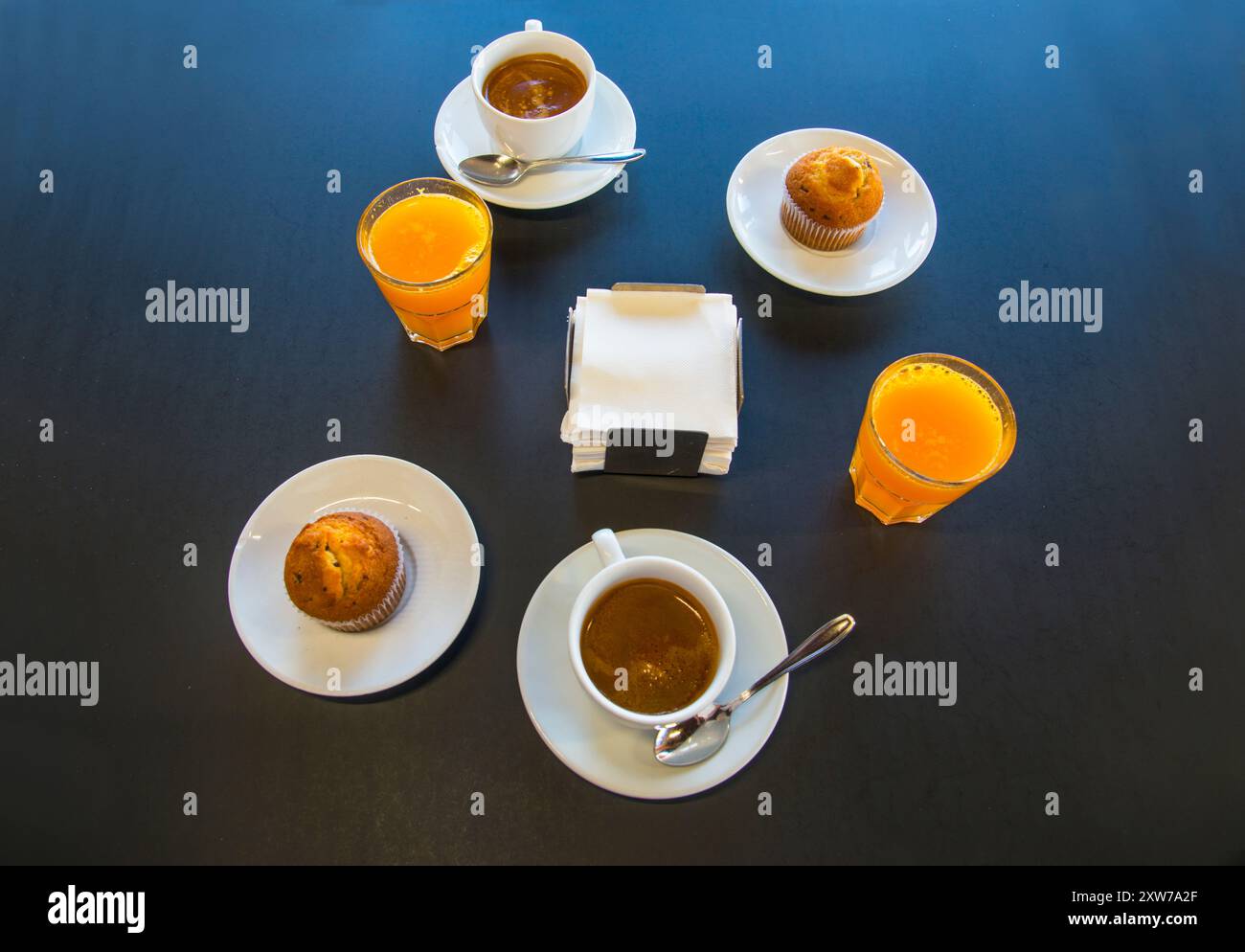 Frühstück: 2 Tassen Kaffee, 2 Orangensäfte und zwei Muffins. Blick von oben. Stockfoto