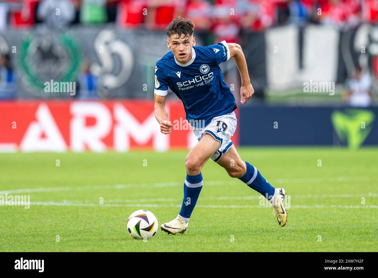 17. August 2024, Nordrhein-Westfalen, Bielefeld: Fußball: DFB-Cup, Arminia Bielefeld - Hannover 96, 1. Runde, Schüco Arena: Bielefelder Maximilian großer läuft mit dem Ball zu seinen Füßen. Foto: David Inderlied/dpa Stockfoto