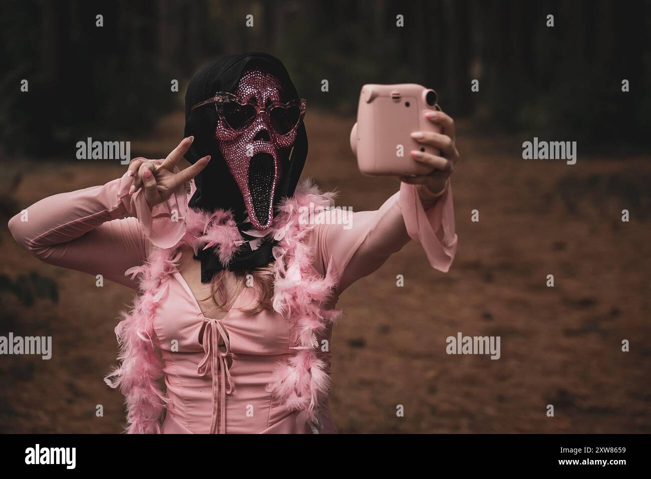 Frau posiert in rosafarbenem Schrei-halloween-Kostüm mit Dorkwald im Hintergrund Stockfoto