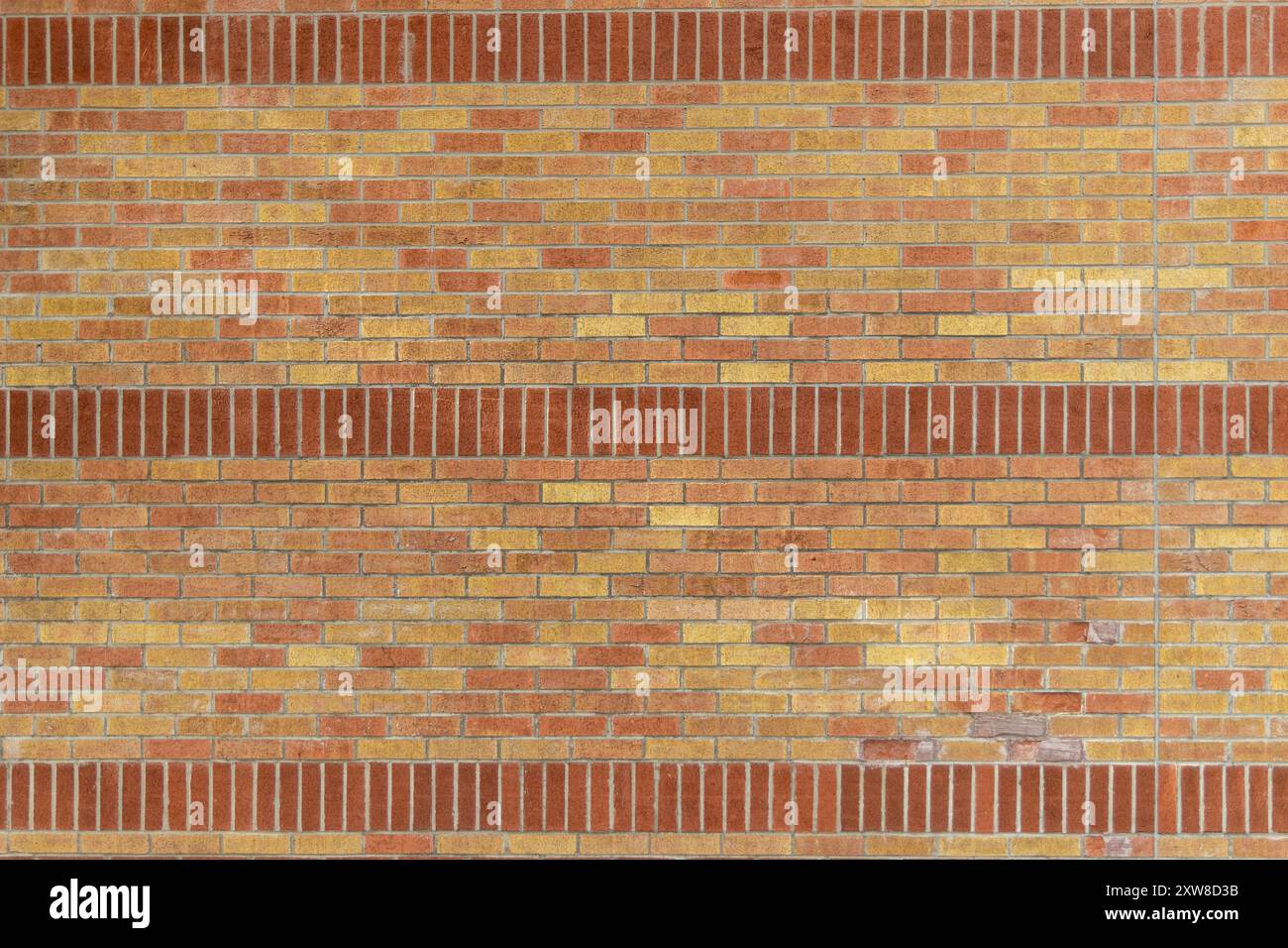 Warme Ziegelwand mit verschiedenen Rot- und Orangetönen, horizontale graue Zementlinien. Aufgenommen in Toronto, Kanada. Stockfoto