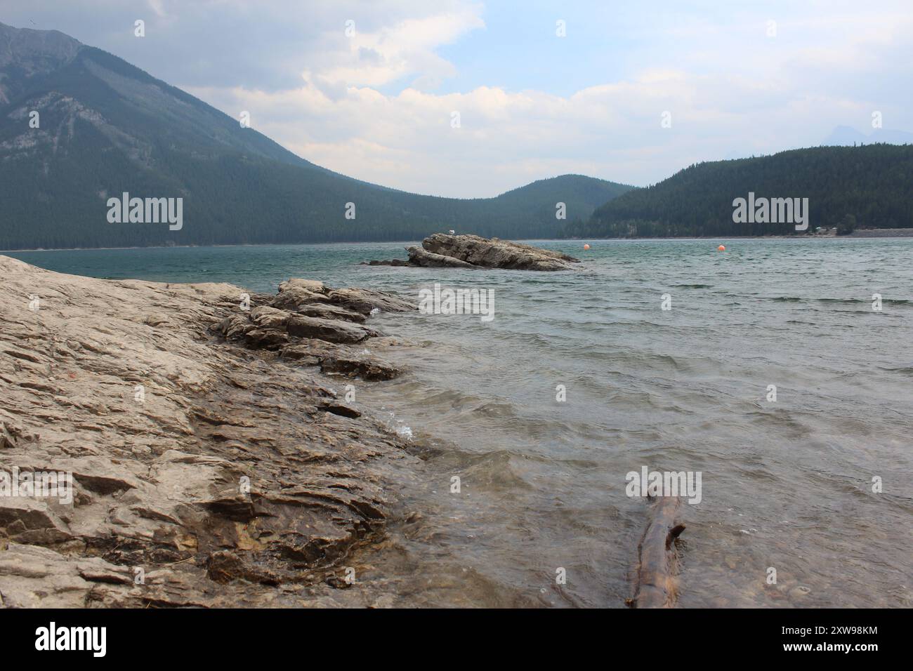 Ein Landschaftsbild der Berge rund um den Lake Minnewanka, aufgenommen vom felsigen Strand im Banff National Park, Kanada (29.07.24) Stockfoto