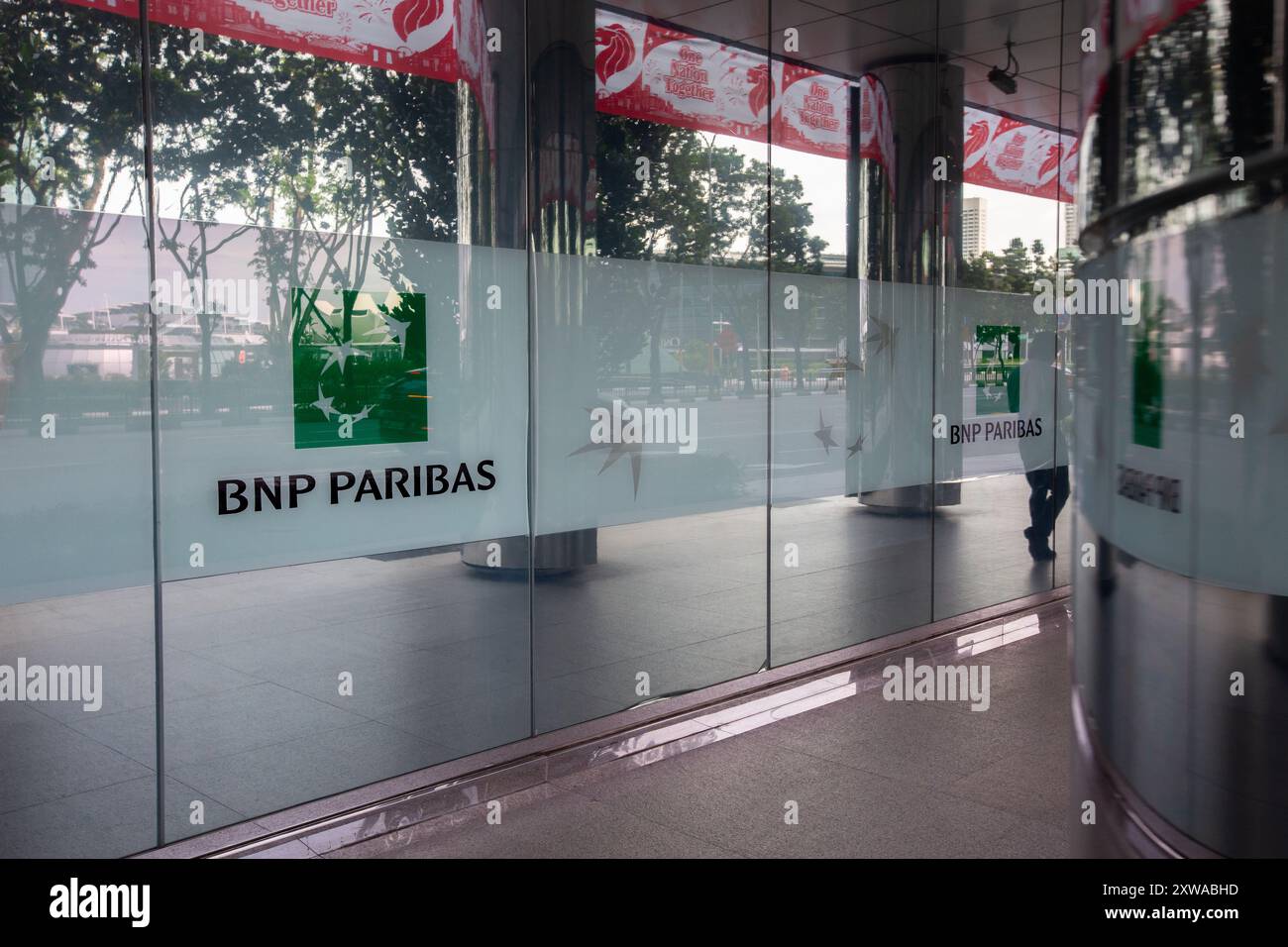 BNP Paribas Logo entlang eines Gebäudes neben einer Straße, um Sichtbarkeit und Marketingzwecke im Erdgeschoss zu zeigen, wo Menschen gehen. Singapur Stockfoto