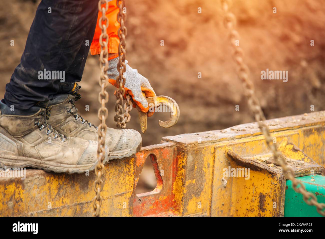 Bauherr Befestigung von Haken und Kette für Hebegeschirr am Schachtkasten des Sicherheitsmanagements zum Heben Stockfoto