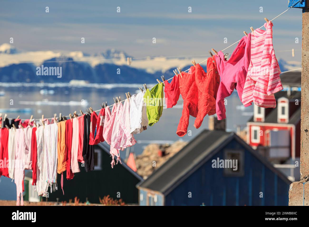 Typische grönländische Häuser an einem Fjord mit Eisbergen und Bergen, sonnig, Ittoqqortoormiit, Scoresby Sund, Ostgrönland, Grönland Stockfoto