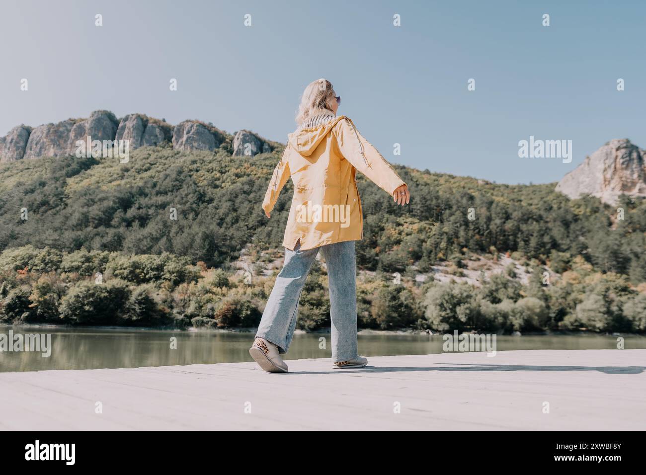 Frau im gelben Regenmantel, die auf einem Holzsteg läuft Stockfoto