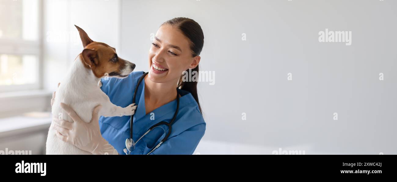 Der Tierarzt hält einen freundlichen Hund und lächelt Stockfoto