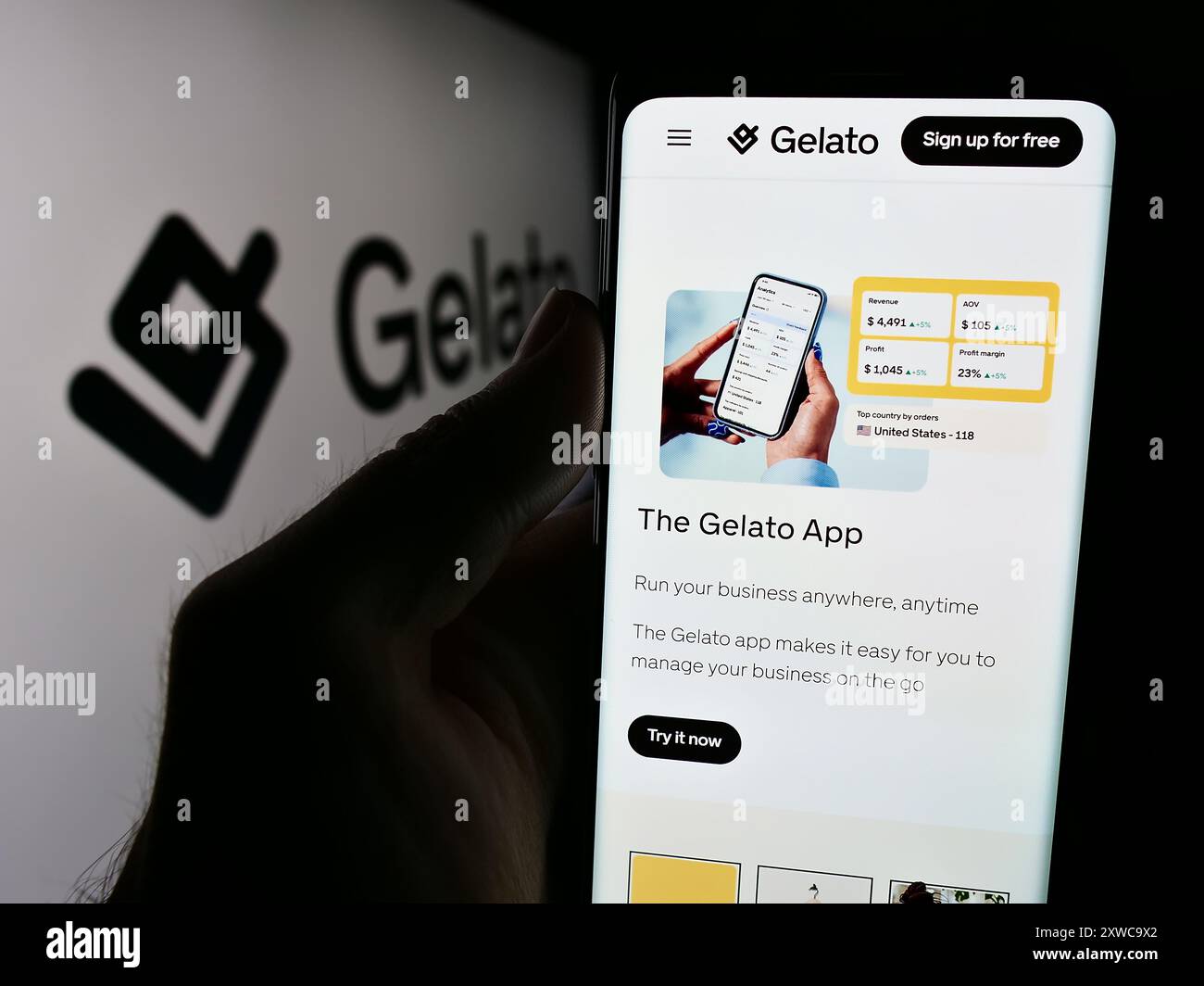 Person mit Mobiltelefon und Website des norwegischen Print-on-Demand-Unternehmens Gelato ASA vor dem Logo. Konzentrieren Sie sich auf die Mitte des Telefondisplays. Stockfoto