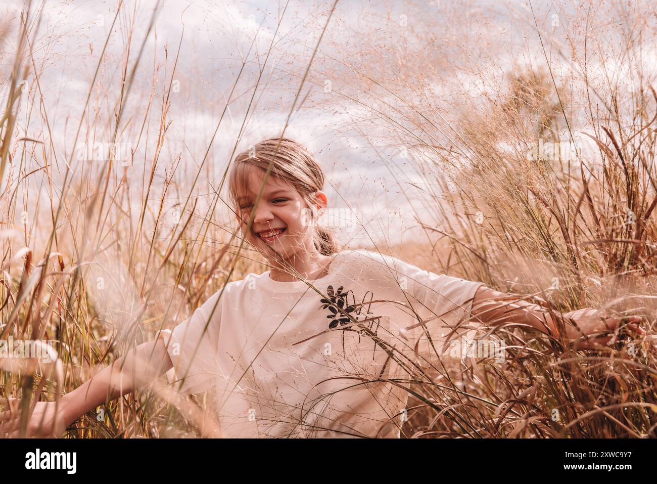 7-Jährige, die mit ihren Haaren im Pferdeschwanz auf einem Feld läuft Stockfoto