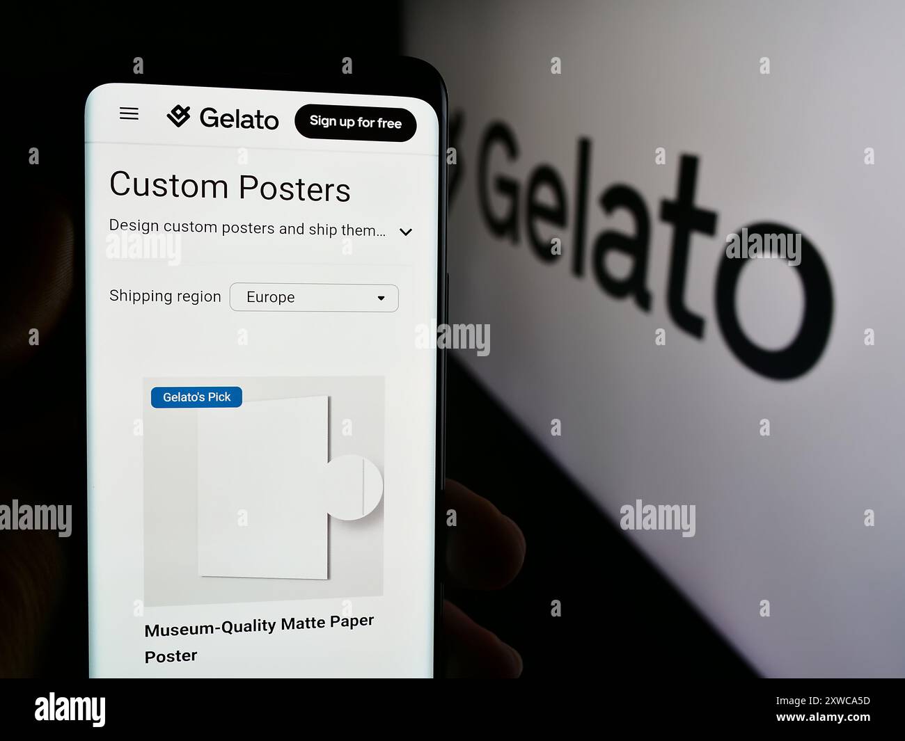 Person mit Smartphone und Webseite des norwegischen Print-on-Demand-Unternehmens Gelato ASA vor dem Logo. Konzentrieren Sie sich auf die Mitte des Telefondisplays. Stockfoto
