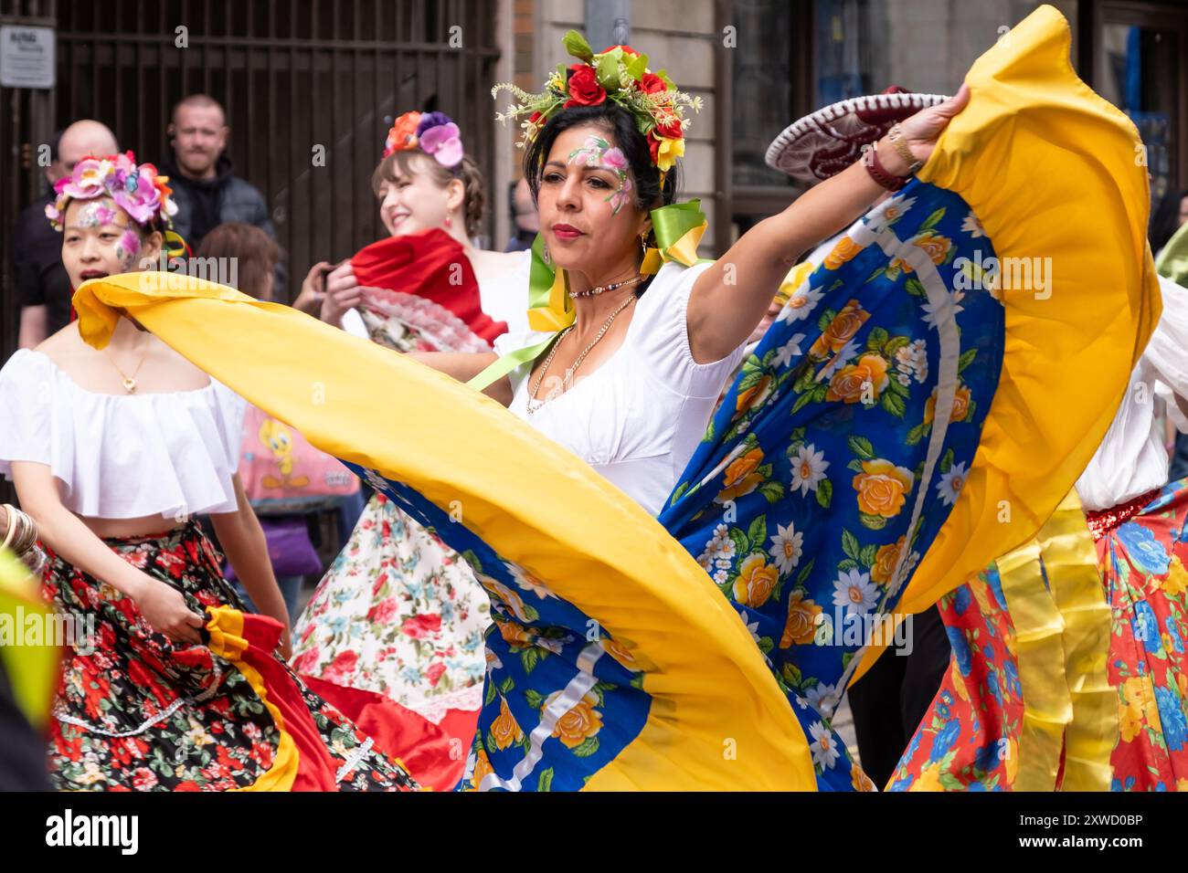 Südamerikanische Frau tanzt bunte Kostüme und wirbelnde Kleider bei der jährlichen multikulturellen Karnevalsparade in Belfast Mela. Belfast, Großbritannien - 17. August 2024. Stockfoto