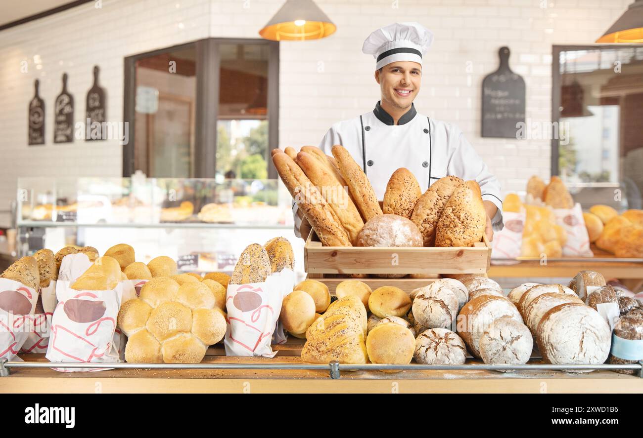 Junger Bäcker, der eine Schachtel mit Brot in einer Bäckerei hält Stockfoto