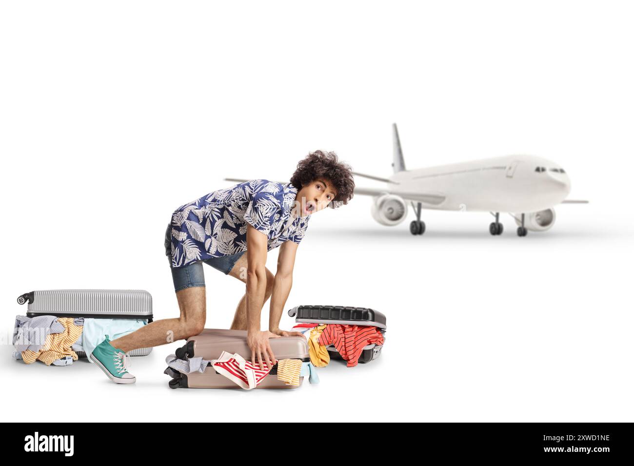 Überraschter junger Mann, der einen Koffer am Flughafen auf weißem Hintergrund packt Stockfoto