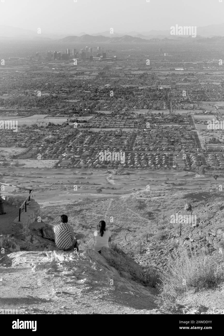Das junge kaukasische Paar sitzt auf einem Felsen am Dobbins Lookout, South Mountain Park, Phoenix, Arizona, USA. Stockfoto