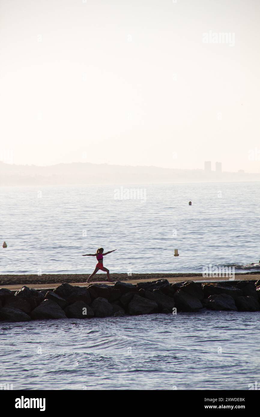 Frau, die bei Sonnenaufgang Yoga macht, in Marbella, Spanien Stockfoto